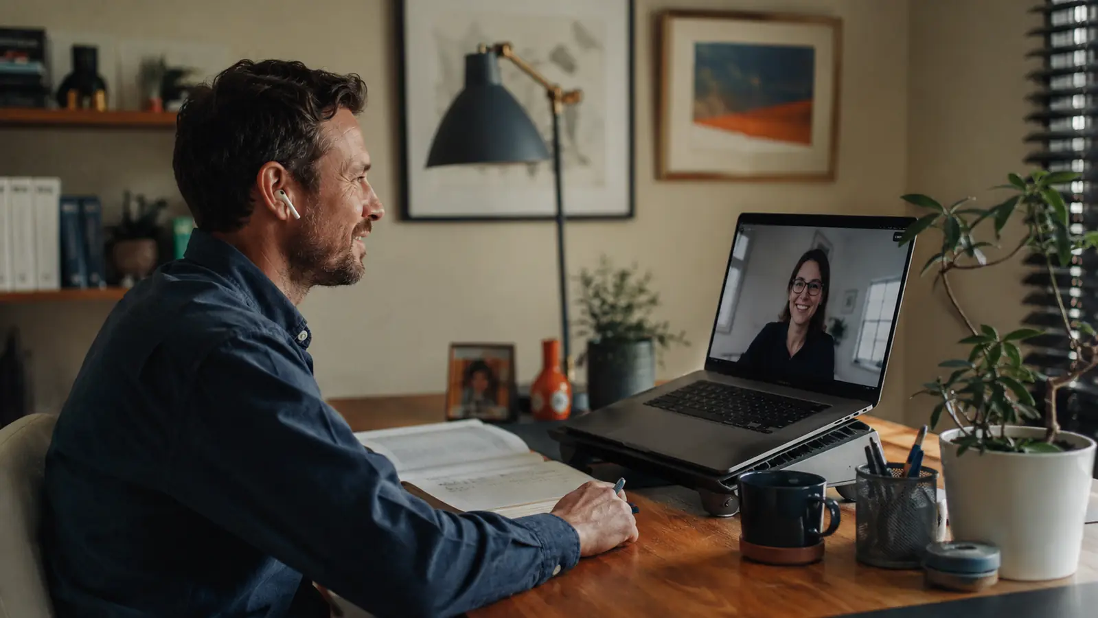 Remote worker mid video call with laptop tilted up on a cooling pad at a home desk