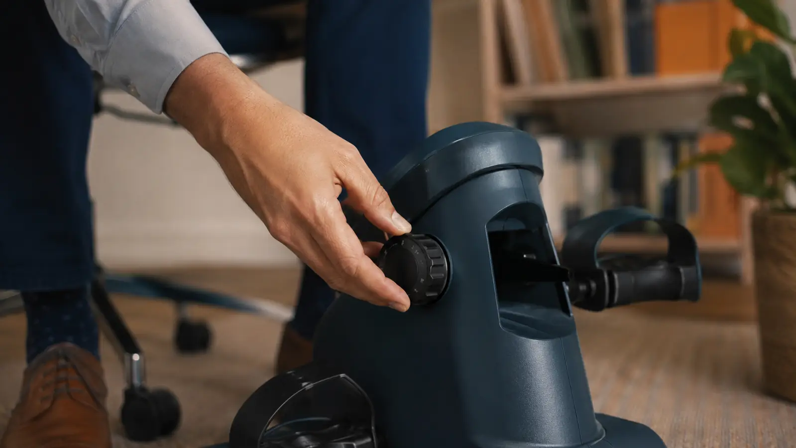 Close-up of a hand adjusting the resistance dial on the himaly pedal exerciser