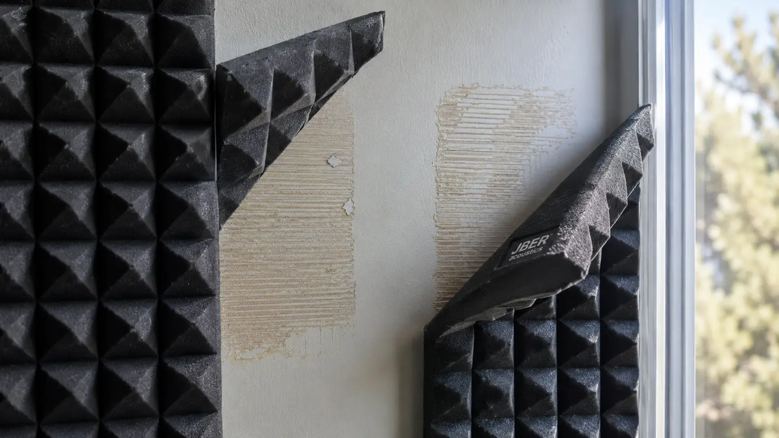 Two peeled-back foam panels showing adhesive residue and slight yellowing after months of use near a sunny window